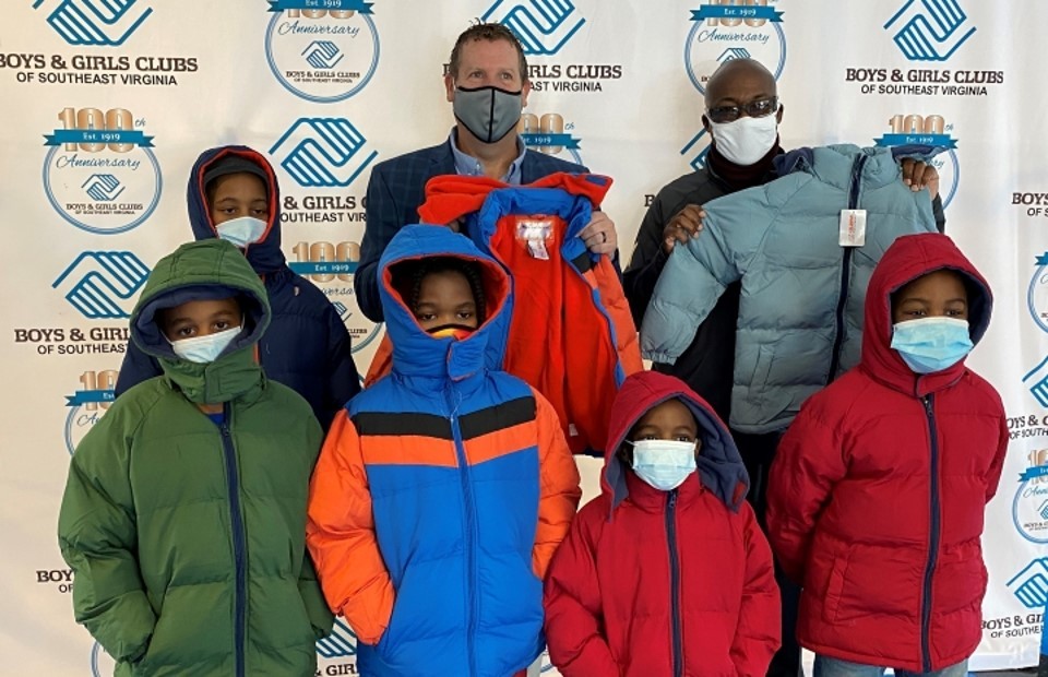Operation Warm - Smaller group of children posing with jackets in front of backdrop