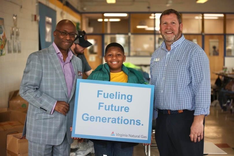 2 men and a child holding a sign